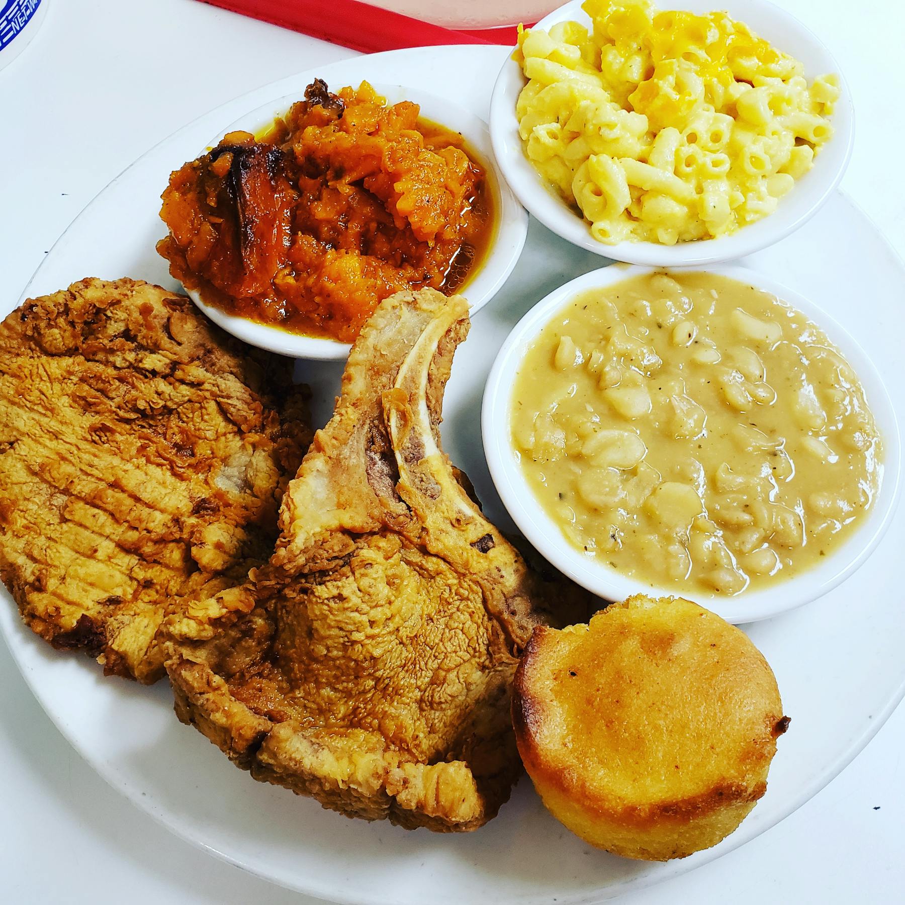 a white plate topped with fried chicken and bowls filled with food